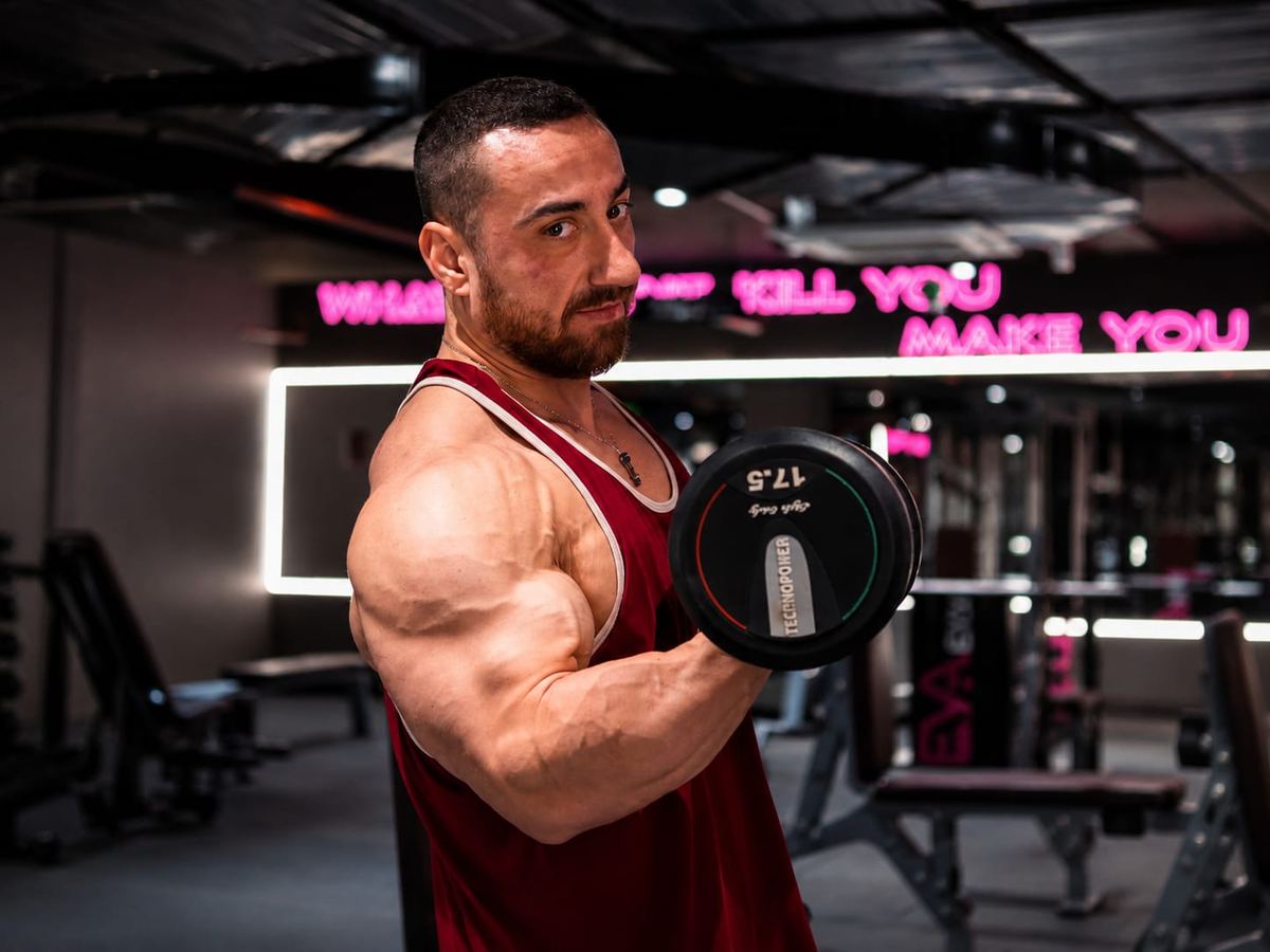 İsmail Yalçın dambılla biceps çalışırken, kameraya bakıyor